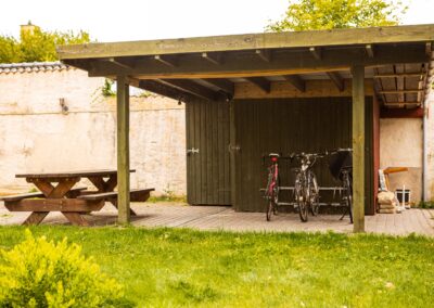 Overdækket terrasse med bord og cykler på HabitusHuset Holbo.