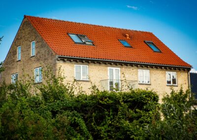 Facade med rødt tegltag og vinduer på HabitusHuset Holbo.