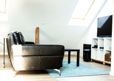 Sort sofa i stueområde med ovenlys på HabitusHuset Holbo.